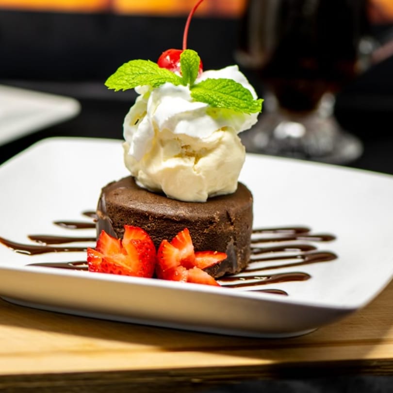 Chocolate lava cake with vanilla ice cream, whipped cream, mint, cherry, and strawberries.