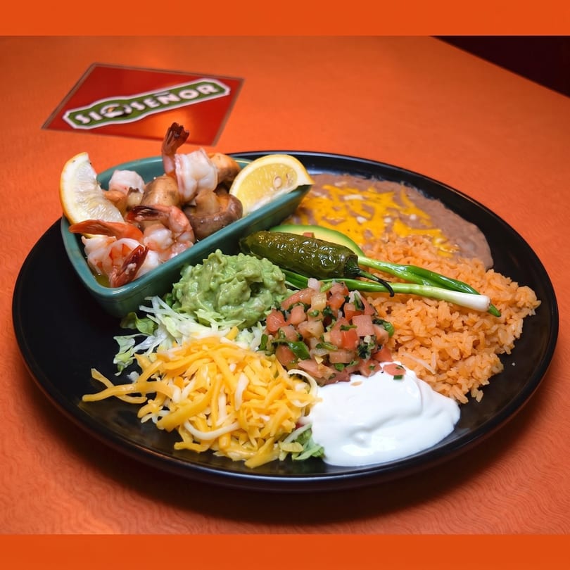 A black plate with shrimp, rice, beans, guacamole, pico de gallo, cheese, and sour cream.