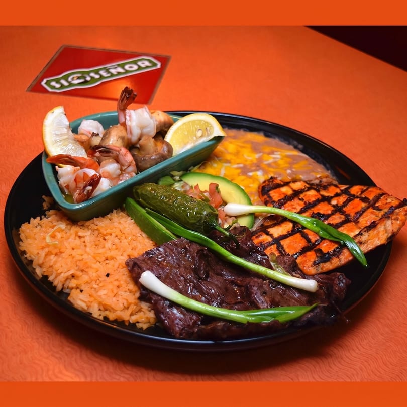 A Si Señor Mexican restaurant platter with grilled steak, chicken, shrimp, rice, beans, and vegetables.